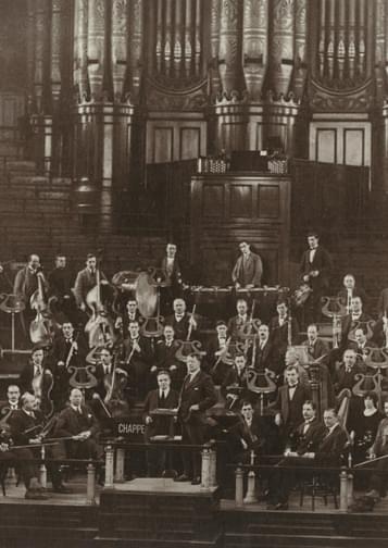 Old black and white photograph of the orchestra's founding members in 1920, in front of the organ at Birmingham Town Hall