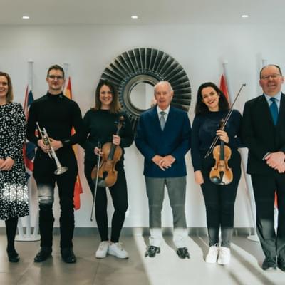 Photograph of 6 people stood together. Three musicians are pictured holding instruments, and between them are two members or CBSO staff along with Sir Peter Rigby.