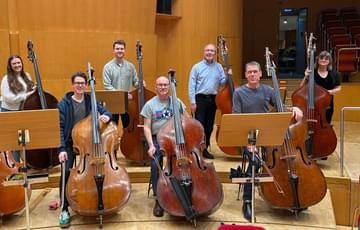Eight double bass and players sitting on stage