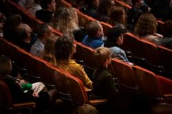 Photograph of a young boy sitting in the concert hall with his mother, father, and sister