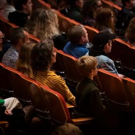 Photograph of a young boy sitting in the concert hall with his mother, father, and sister