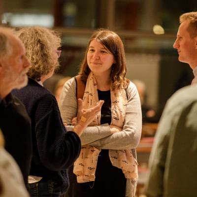 Photograph of a young woman talking to friends in Symphony Hall's foyer