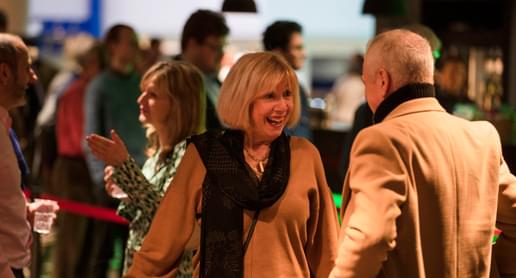 Photograph of a woman smiling and talking to a friend in the Symphony Hall foyer