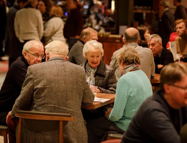 Photograph of a group of friends sitting and talking at a table in the Symphony Hall foyer
