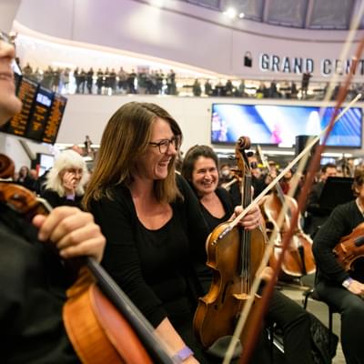 Photograph of Amy Thomas and the viola section laughing whilst performing in New Street train station
