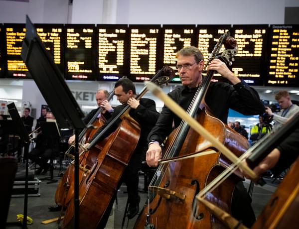 Photograph of Julian Atkinson and the double bass section performing at New Street station