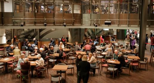 People sit and stand talking in the Jennifer Blackwell Performance Space