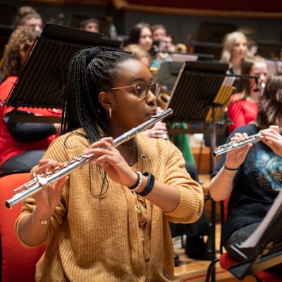 Photograph of a teenage girl playing the flute in a Project Remix rehearsal