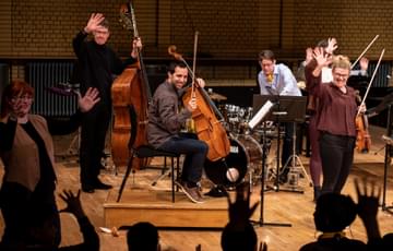 Photograph of string players waving to the audience during a Relaxed Concert