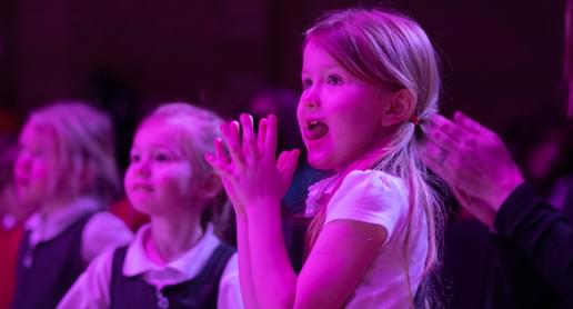 Photograph of a school child clapping whilst watching a performance