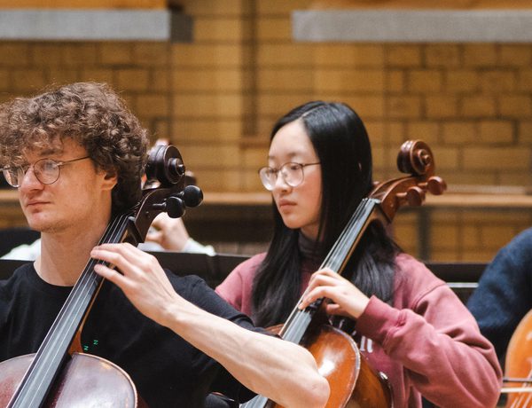 Photo of three young cellists playing in a rehearsal.