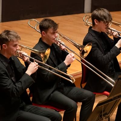 three young men playing the trombone