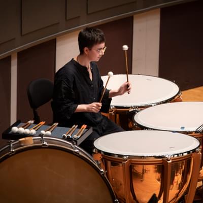 young girl with short hair playing the timpani