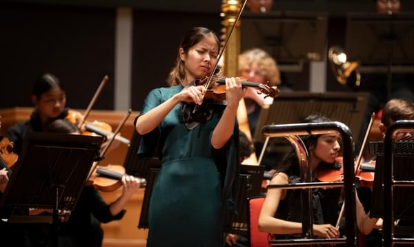young woman playing the violin in a green dress