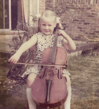 Helen Edgar is pictured at as a child playing the cello. Helen is sat outside. The image is slightly muted in colour due to age.