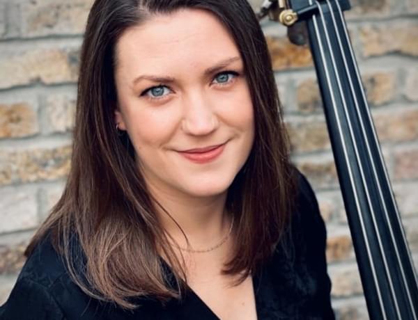 Headshot of double bassist Aisling Reilly. Aisling is stood with her double bass.