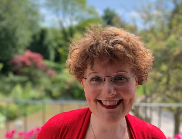 Headshot of harpist Katherine Thomas. Katherine is outside surrounded by greenery.