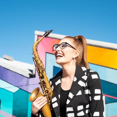 Photograph of Jess Gillam laughing and holding her saxophone.