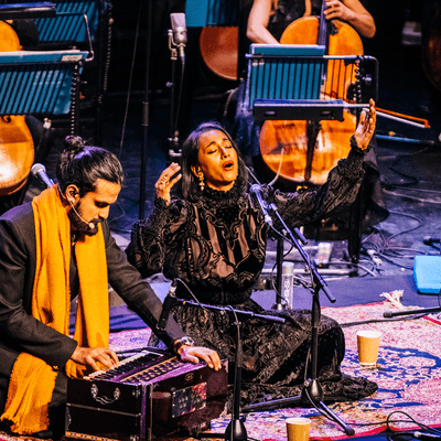 Photograph of two musicians sitting cross-legged on the floor to perform at Symphony Hall.