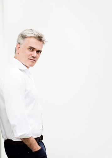 Edward Gardner leaning against a white wall